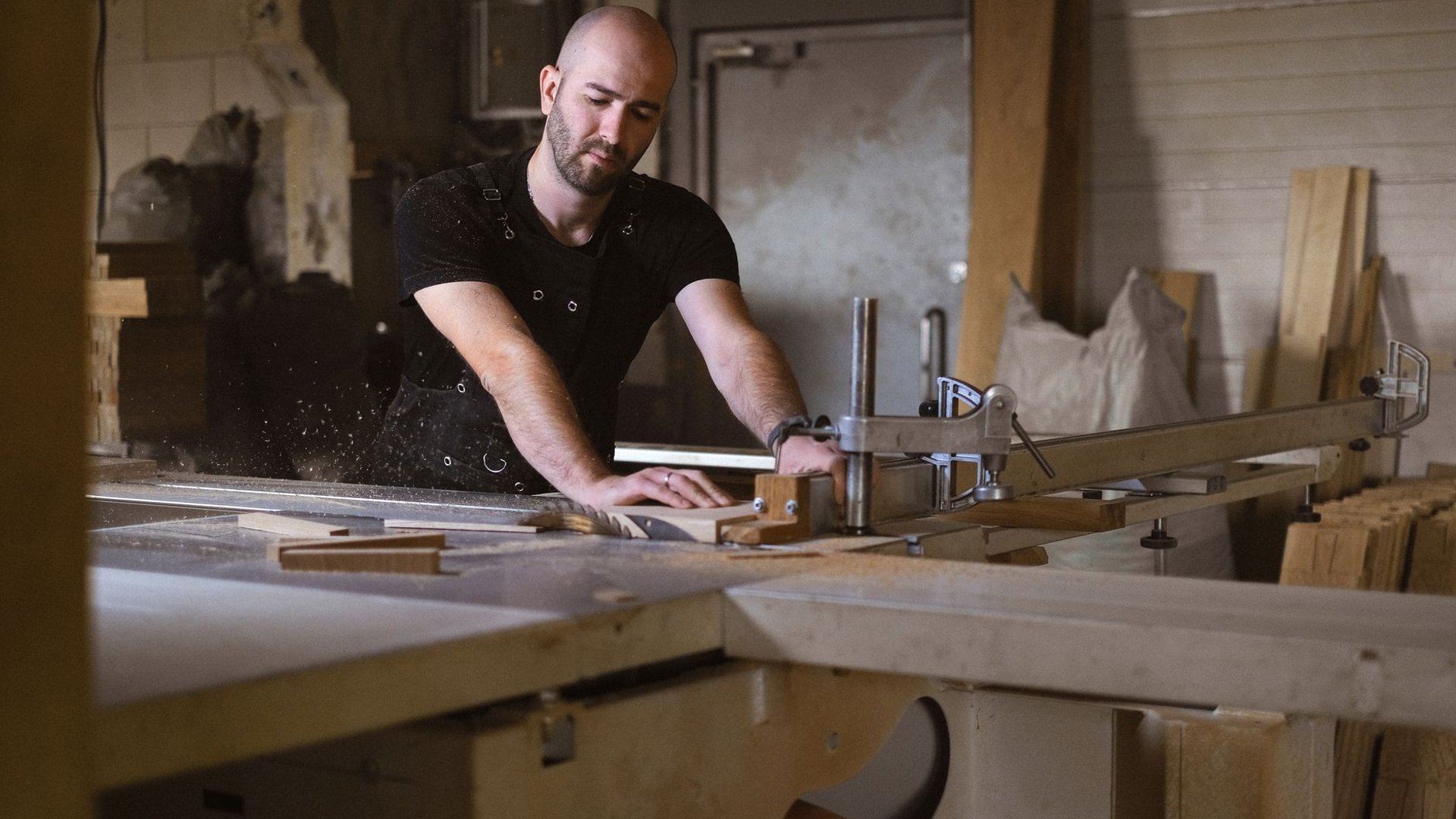 Tischler bearbeitet Holz in einer Werkstatt mit Werkbank und Maschinen