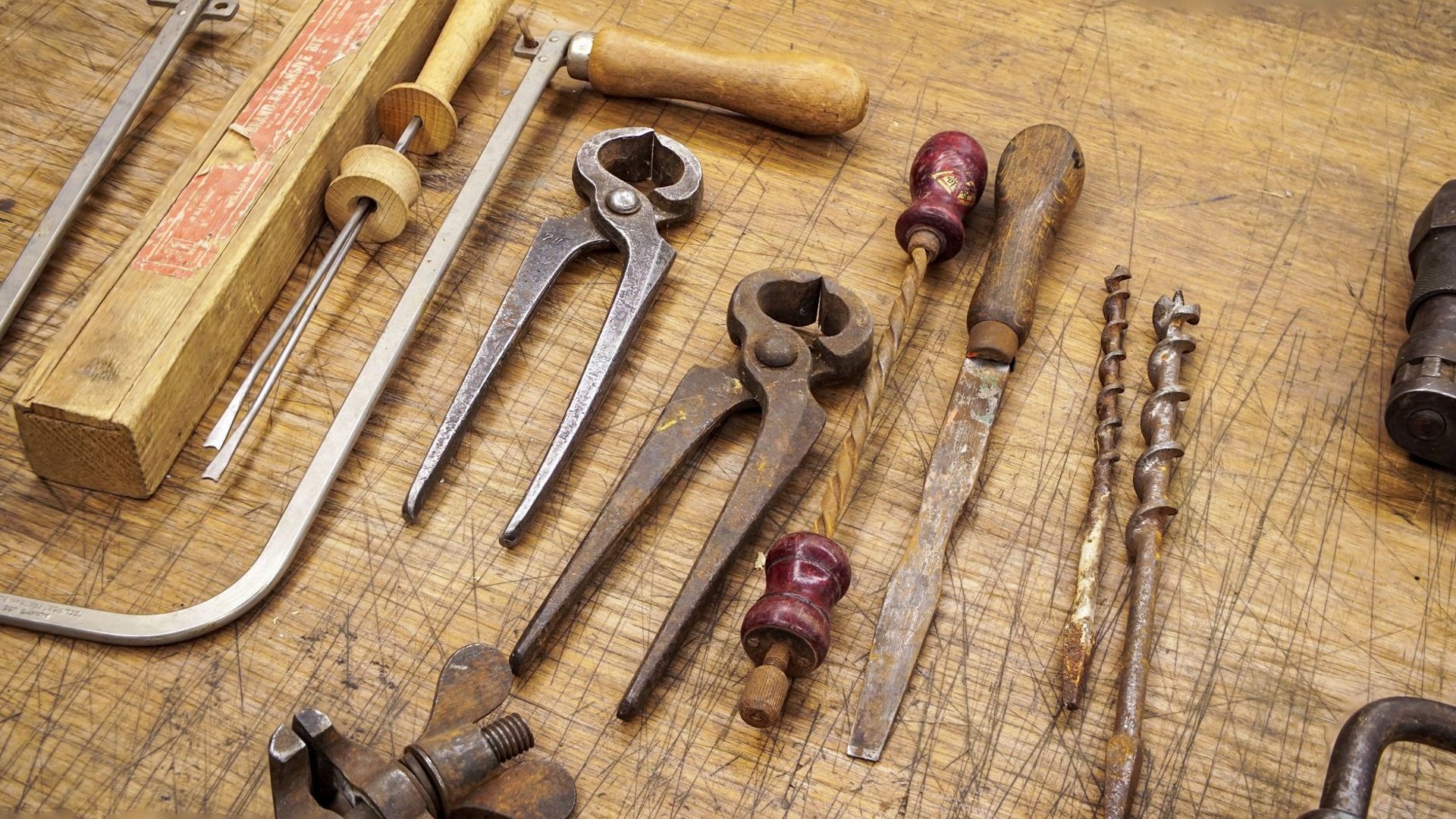 Altes Handwerkzeug auf einer abgenutzten Holz-Werkbankplatte