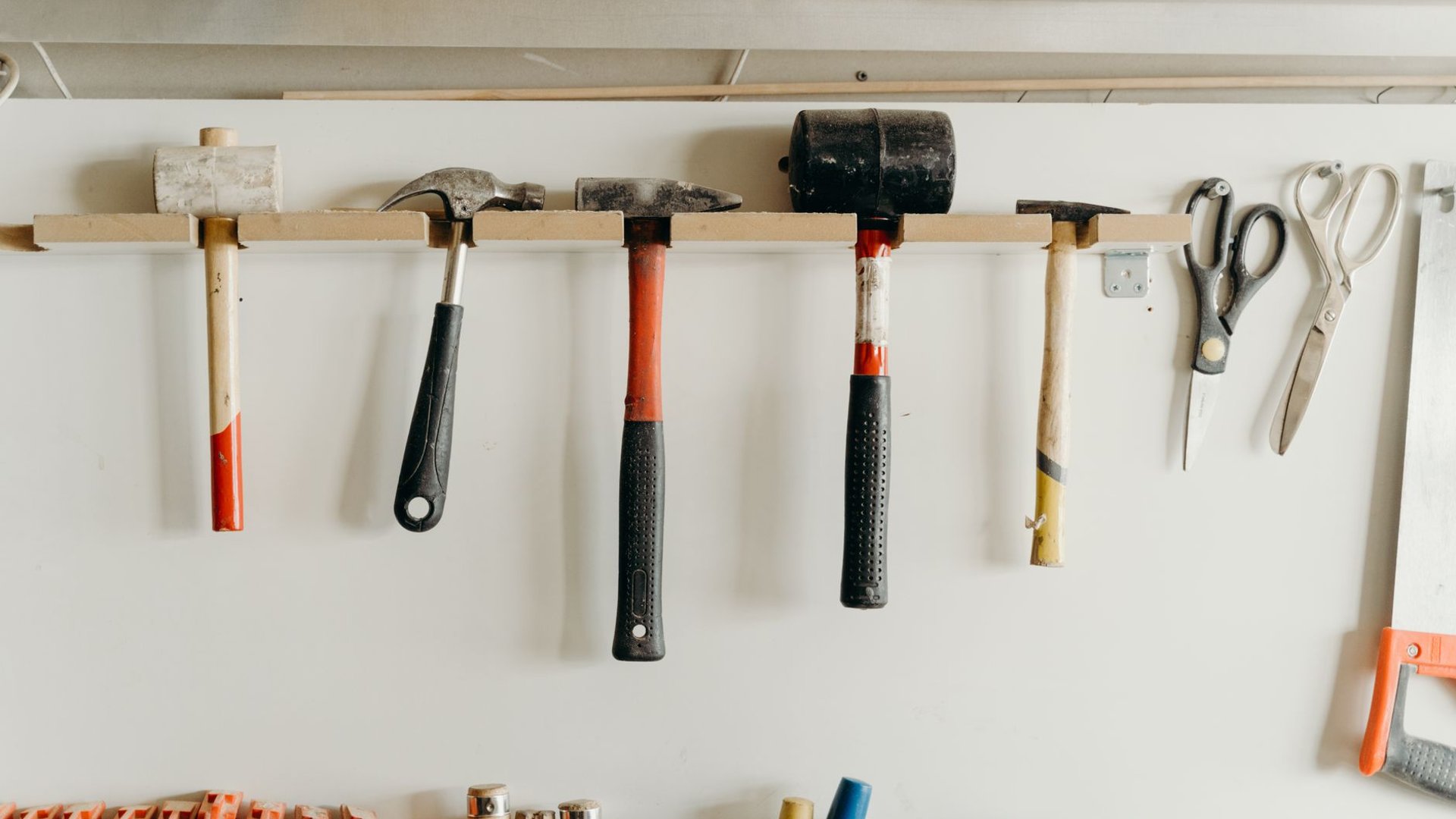 Selbst gebaute Werkzeugwand mit Hammerleiste und Scheren an heller Werkstattwand